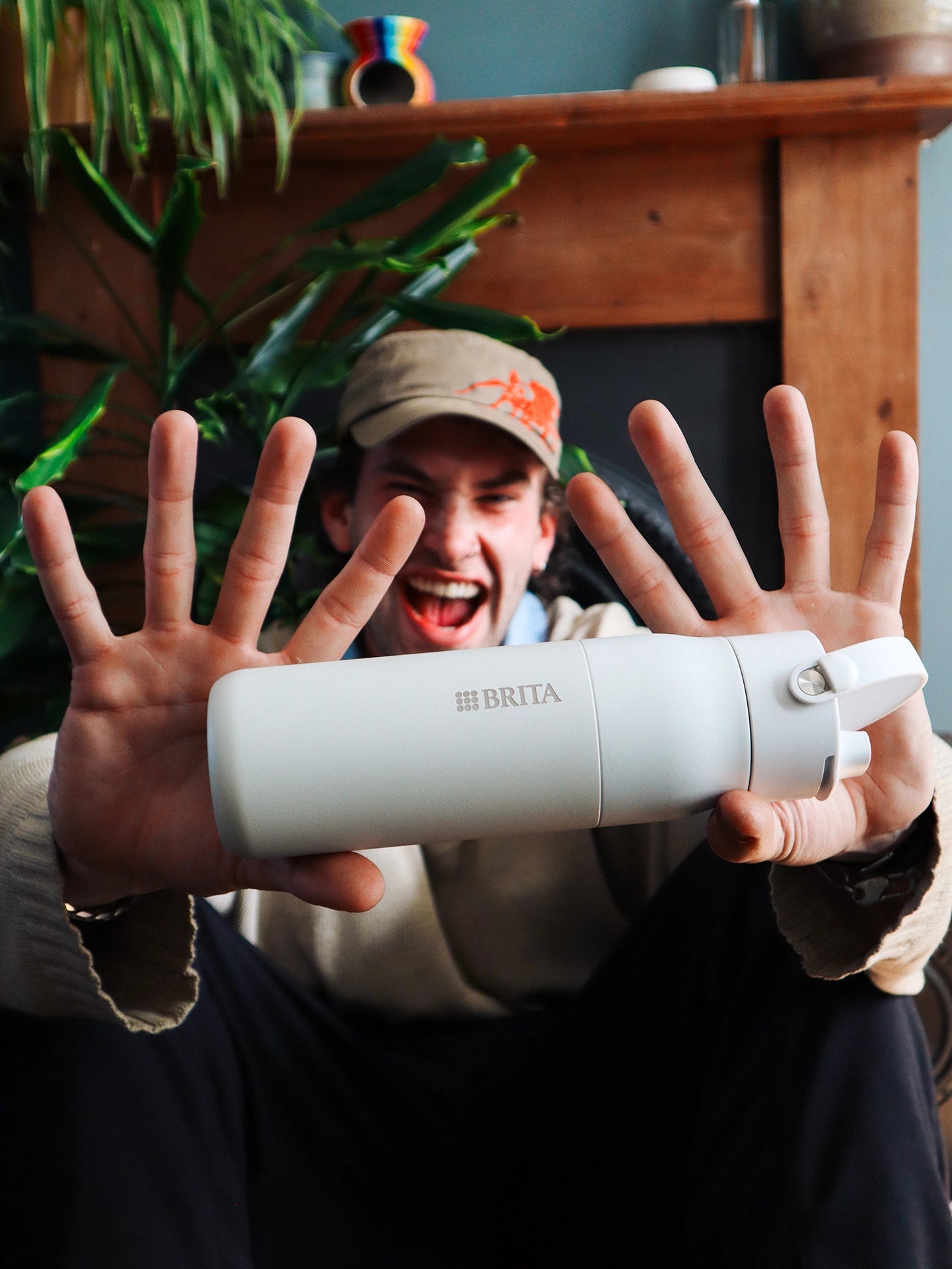 Person presenting a white BRITA LARQ Filter Bottle in a living room setting.