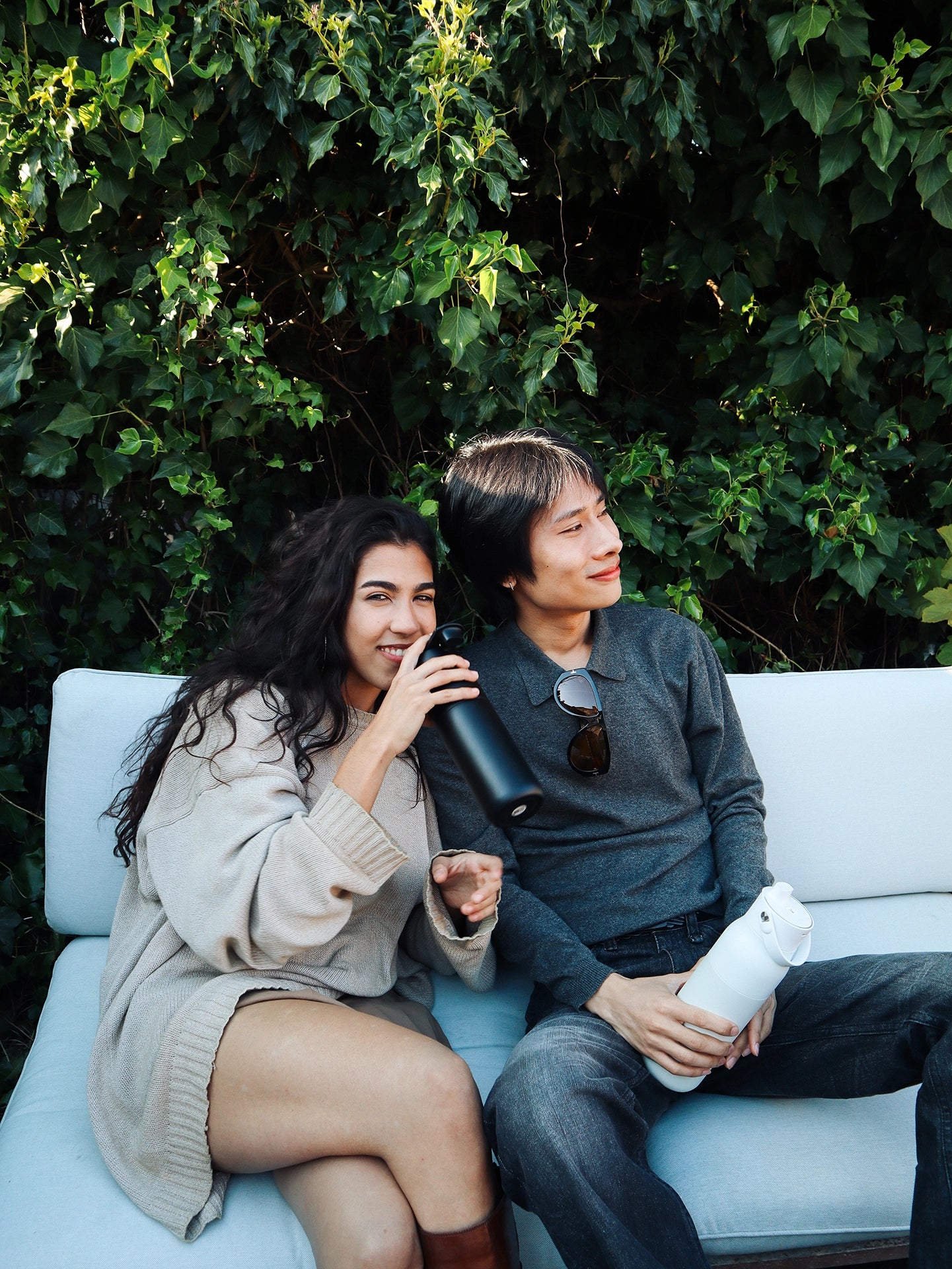 Two young people relaxing outdoors with black and white BRITA LARQ Filter Bottles.