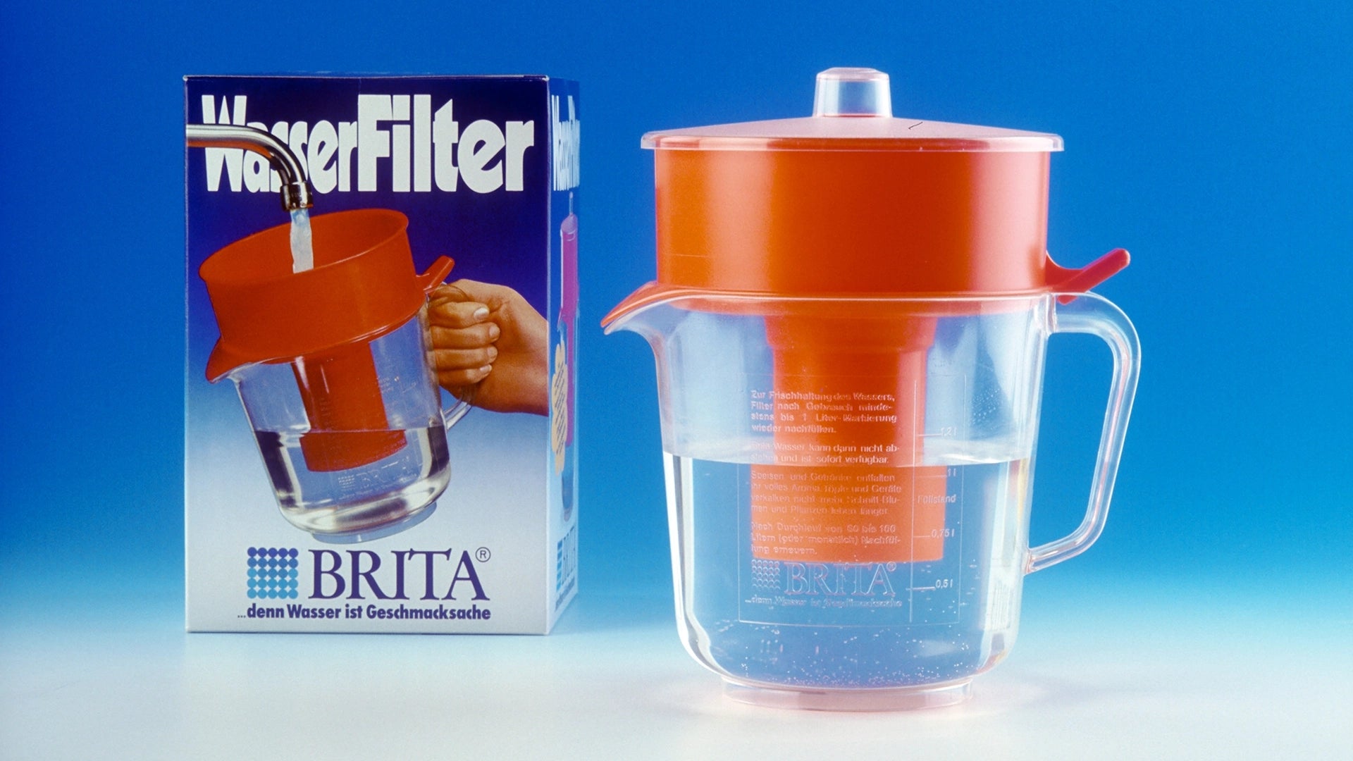 Orange BRITA water filter jug with packaging on a blue background.