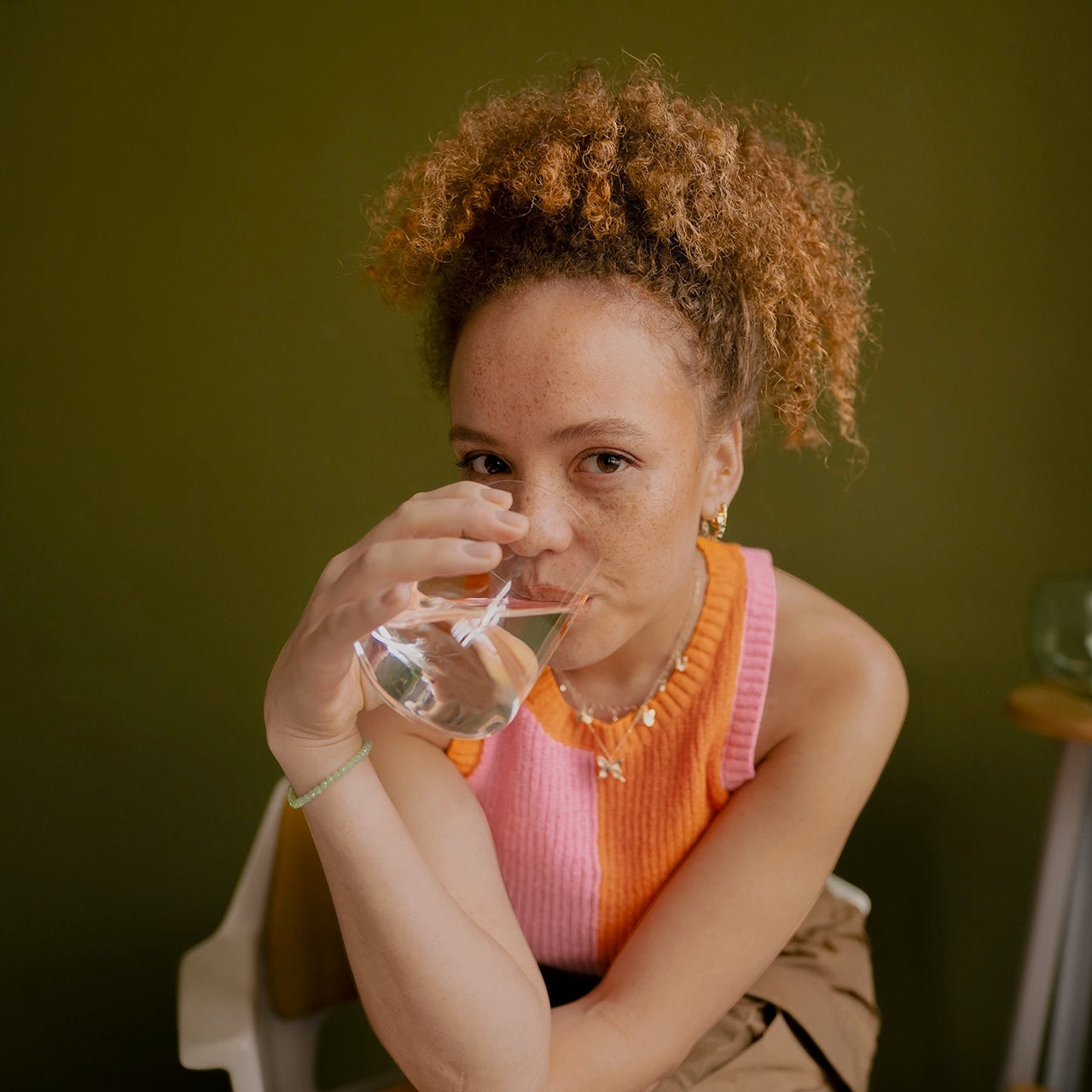 Une personne tenant un verre d'eau devant un fond vert