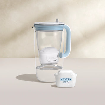 A water filter glass jug in blue on a beige background