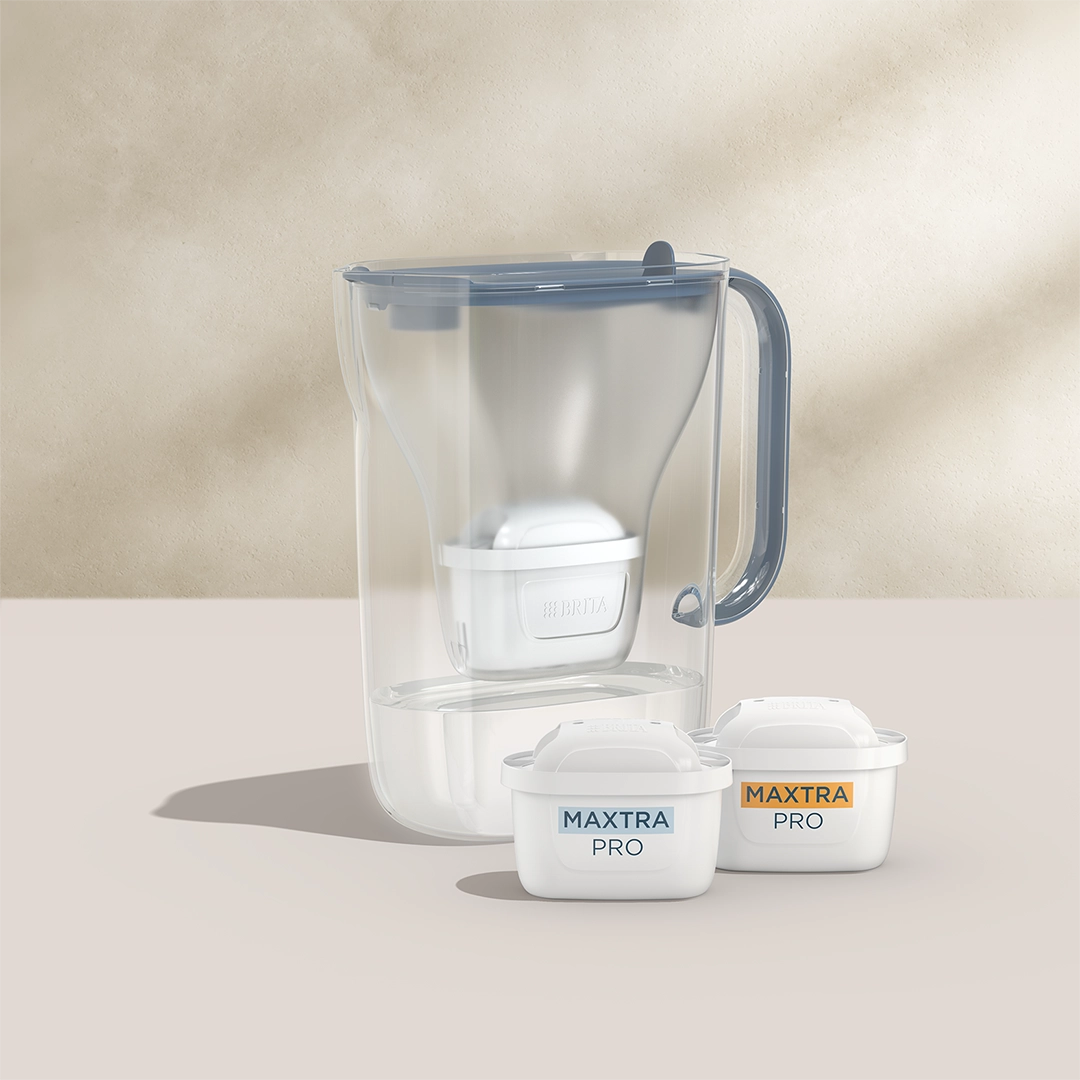 BRITA Style Essential en bleu avec deux cartouches filtrantes MAXTRA PRO sur fond beige.