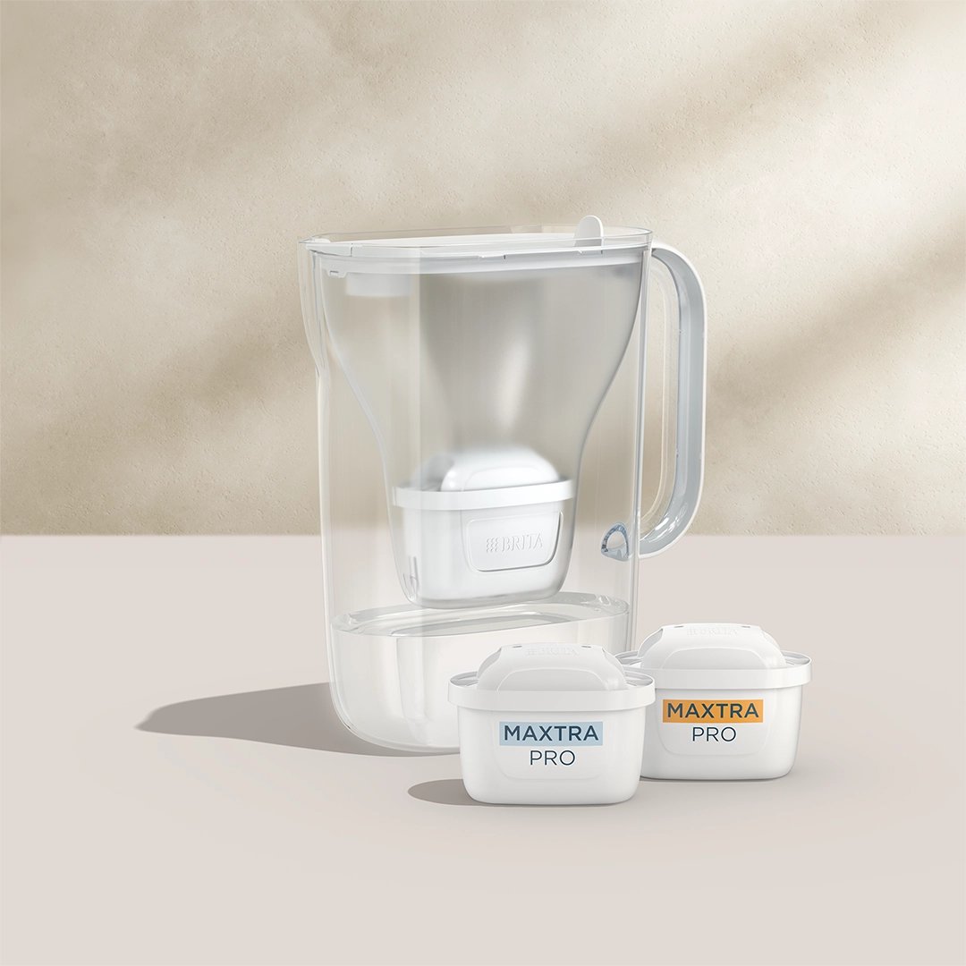 BRITA Style Essential en blanc avec deux cartouches filtrantes MAXTRA PRO sur fond beige.